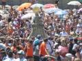 Procesión con imagen religiosa en medio de una multitud en una playa.