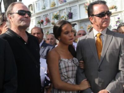 Una imagen de un funeral con flores y un hombre en un traje de negocios.