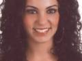 Una mujer con cabello oscuro y ondulado, sonriendo.