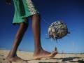 Un niño camina por el desierto con una pelota hecha de materiales reciclados en su mano.