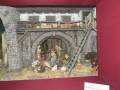 Un diorama medieval con una escena de trabajo en un almacén. Personas trabajando, animales y herramientas antiguas.