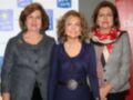 Tres mujeres sonrientes posan juntas frente a un fondo con logotipos de organizaciones. La imagen parece ser de una celebración o evento formal, posiblemente relacionado con la política o el deporte.