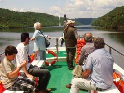 Pasajeros disfrutando de un paseo en barco por el río, con paisajes montañosos alrededor.