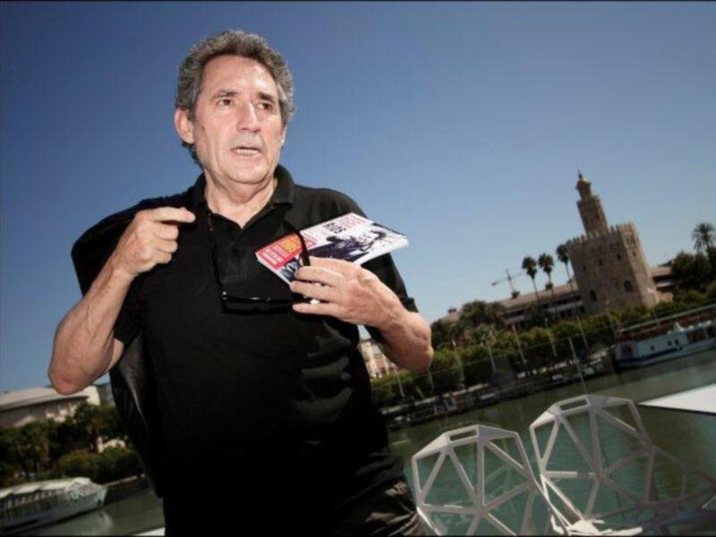 Un hombre sostiene una revista con la Torre del Oro en el fondo, en Sevilla, España.