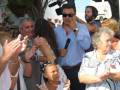 Celebración en una plaza con personas intercambiando saludos y aplaudiendo.