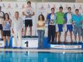 Equipo ganador de una competición de natación, celebrando en el podio con trofeos.