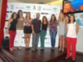 Las mujeres posan en un escenario con banners de Andalucía y una imagen de un niño jugando baloncesto en la pantalla.
