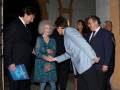 Persona saludando a una mujer mayor en un evento formal en un patio histórico.