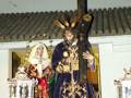 Estatua religiosa con vestimentas tradicionales y un crucifijo en la mano, posiblemente durante una celebración religiosa.