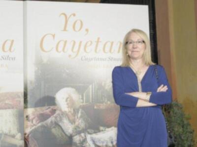 Persona posando frente a un cartel con el título 'Yo, Cayetana' y una imagen de una mujer en un sofá.