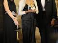 Tres personas elegantes posando formalmente en un evento de gala.