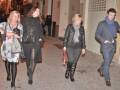 Cuatro personas caminando juntas en una calle adoquinada de la noche, vestidas con ropa de invierno