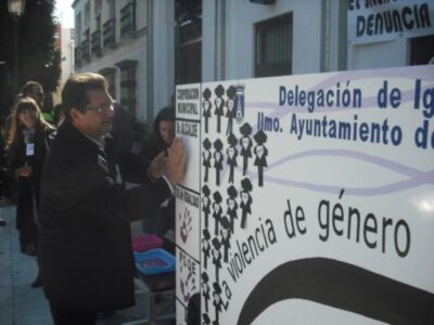 Persona colocando una mano en un panel informativo sobre la violencia de género en una actividad pública.