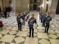 Guardia de honor en la Catedral de Sevilla, vestidos con uniformes tradicionales y tocando cornetas.