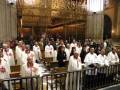 Una iglesia llena de personas vestidas con vestidos blancos y rojos, posiblemente durante una ceremonia religiosa.