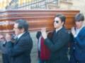 Los hombres están portando un ataúd de madera en una ceremonia fúnebre.