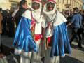 Personajes vestidos con trajes tradicionales participan en una celebración o evento público en una plaza histórica.