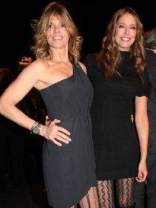Dos mujeres en vestidos negros posan juntas en un evento formal.