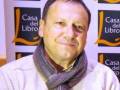 Un hombre con una camisa blanca y un cuello de bufanda, frente a un fondo con el logo de Casa del Libro.