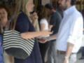 Una mujer con un bolso a rayas hablando con una persona en un evento.