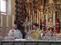 Sacerdotes celebrando una misa en un altar ornado con candelabros y flores, en un entorno religioso.