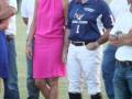 Una pareja en un evento de polo, la mujer con vestido rosa y el hombre con uniforme de polo.