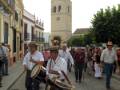 Desfile tradicional en una calle de la ciudad, con músicos tocando tambores y otros participantes.