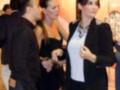 Una mujer en un evento, posando con una camisa blanca y un abrigo negro. Detalles de la imagen: vestimenta formal, ambiente social, probablemente un evento o fiesta.