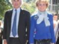 Dos personas vestidas formalmente, uno con traje y corbata, la otra con chaqueta azul y bufanda.