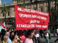Miles de personas protestan con un gran cartel rojo que dice: "Millones para los banqueros, despidos para los obreros. ¡Basta ya! A la Asamblea 15M, Terro-Amate." En el fondo, se puede ver un edificio histórico con columnas y palmeras.