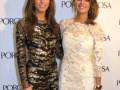 Dos mujeres posan juntas en un evento, uno con vestido de lentejuelas y la otra con vestido floral. La imagen es parte de una celebración por Porcelanosa.