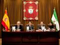 Reunión oficial en un ambiente formal con banderas españolas y andaluzas en el fondo.