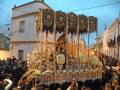 Festividad religiosa en una ciudad con una procesión de alta estación, destacando la elaborada imagen central.