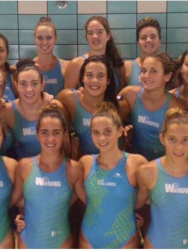 Equipo de natación femenina posando en la piscina.