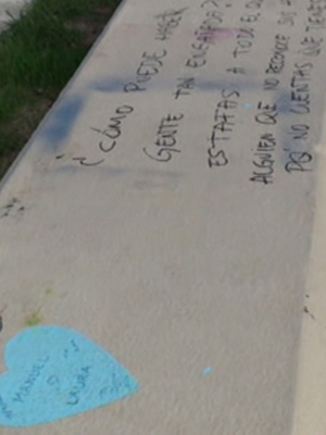 Grafiti en el borde de la acera con un corazón azul y letras desordenadas.
