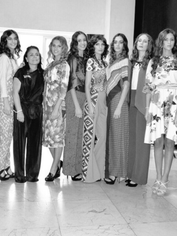 Desfile de moda con modelos posando en trajes de diseño variado en un ambiente interior.