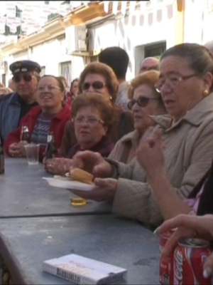 Una multitud de personas disfruta de una comida en un ambiente festivo, con bebidas y comidas apetitosas.