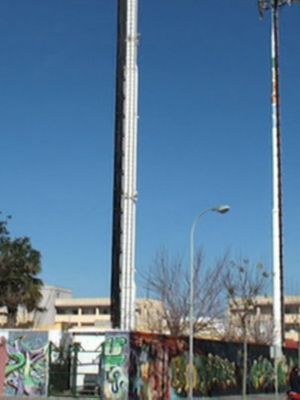 Urban street scene with tall poles, graffiti-covered walls, and clear blue sky.