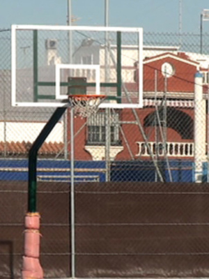 Canasta de baloncesto en un área deportiva con edificios en el fondo.