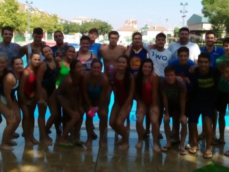 Equipo de natación posando junto a la piscina al aire libre.
