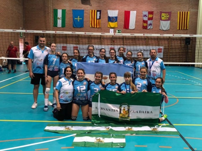 Equipo de voleibol femenino posando con bandera de Guadaira en una cancha deportiva.