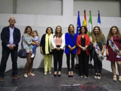 Una familia y amigos posan frente a una pared blanca con banderas de diferentes países. La imagen muestra un ambiente festivo o formal, posiblemente en una celebración o evento.