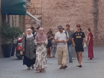 Personas caminando por una calle con edificios de ladrillo.