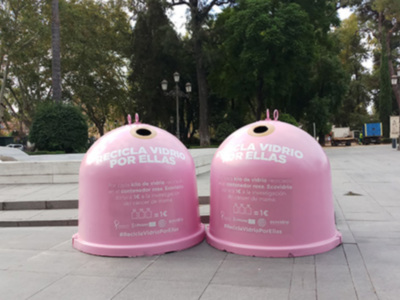 Dos contenedores de basura rosa con mensajes sobre reciclaje en un parque urbano.