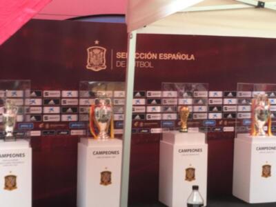 Tres trofeos de fútbol en stands con la bandera española y el escudo de la selección española.