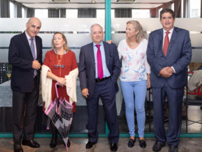 Una imagen de cinco personas posando juntas en un entorno profesional. La escena parece ser una reunión o evento formal, con los hombres vestidos de traje y las mujeres con ropa más casual. La iluminación es buena, sugiriendo que la foto fue tomada en un lugar con ventanas.