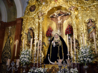 Altar de oro con estatuas religiosas y flores en una iglesia