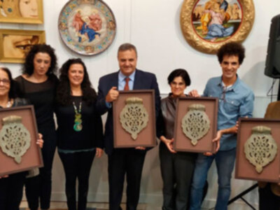 Una imagen de una ceremonia de premiación donde varios individuos sostienen trofeos con diseños geométricos, posiblemente en un evento cultural o académico.