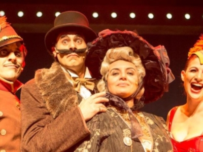 Personas vestidas de época con sombreros y plumas, posiblemente en una representación teatral.
