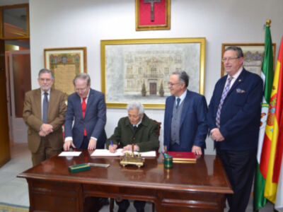 Una reunión formal en un despacho con cuatro personas sentadas alrededor de una mesa de madera. La imagen muestra a dos hombres firmando un documento mientras otros dos observan. En el fondo, hay una bandera y un cuadro con una cruz. La decoración incluye un marco dorado en la pared y un escritorio con una pluma y un bolígrafo.